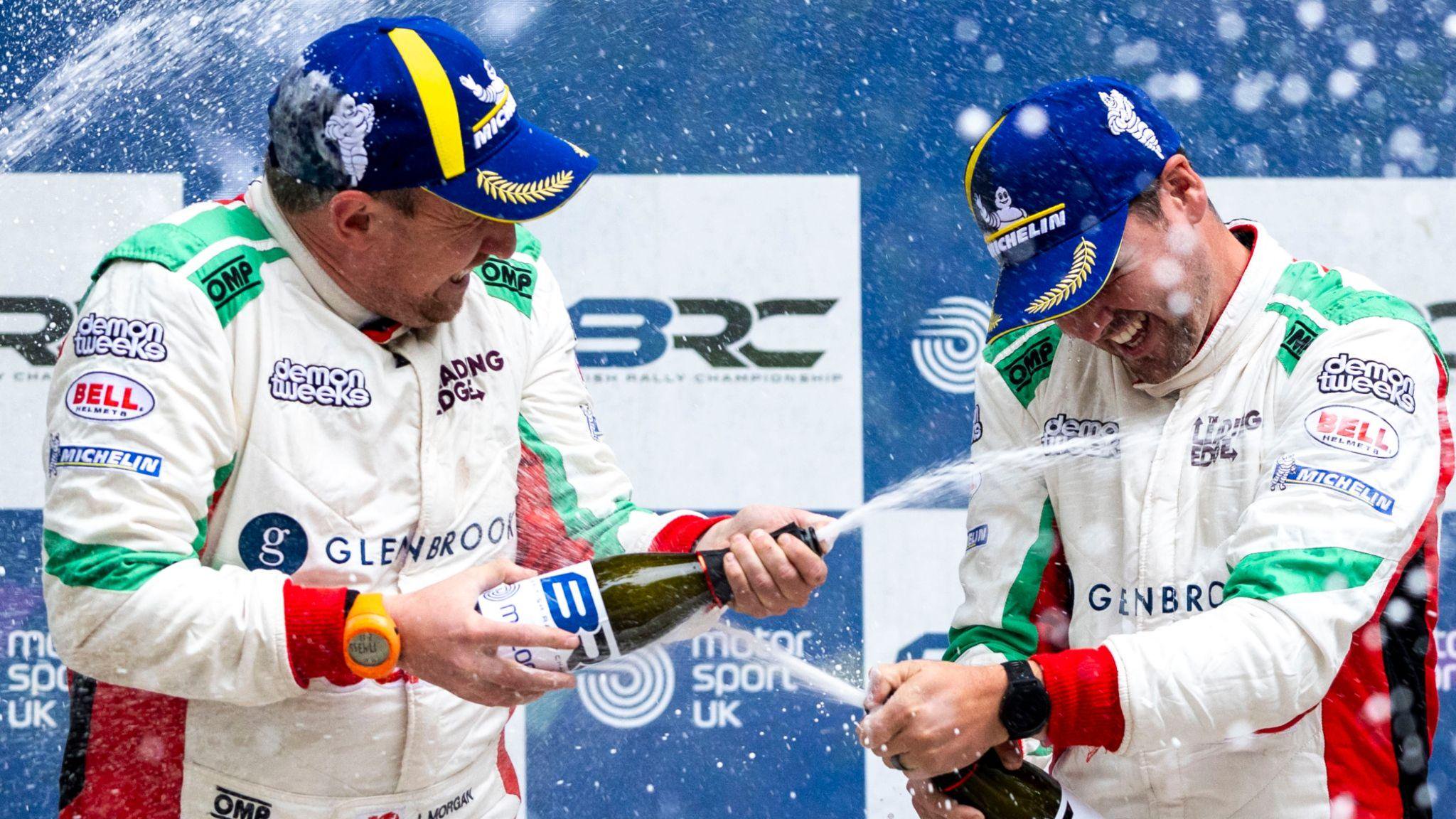 Osian Pryce and co-driver James Morgan shower each other with champagne on a podium