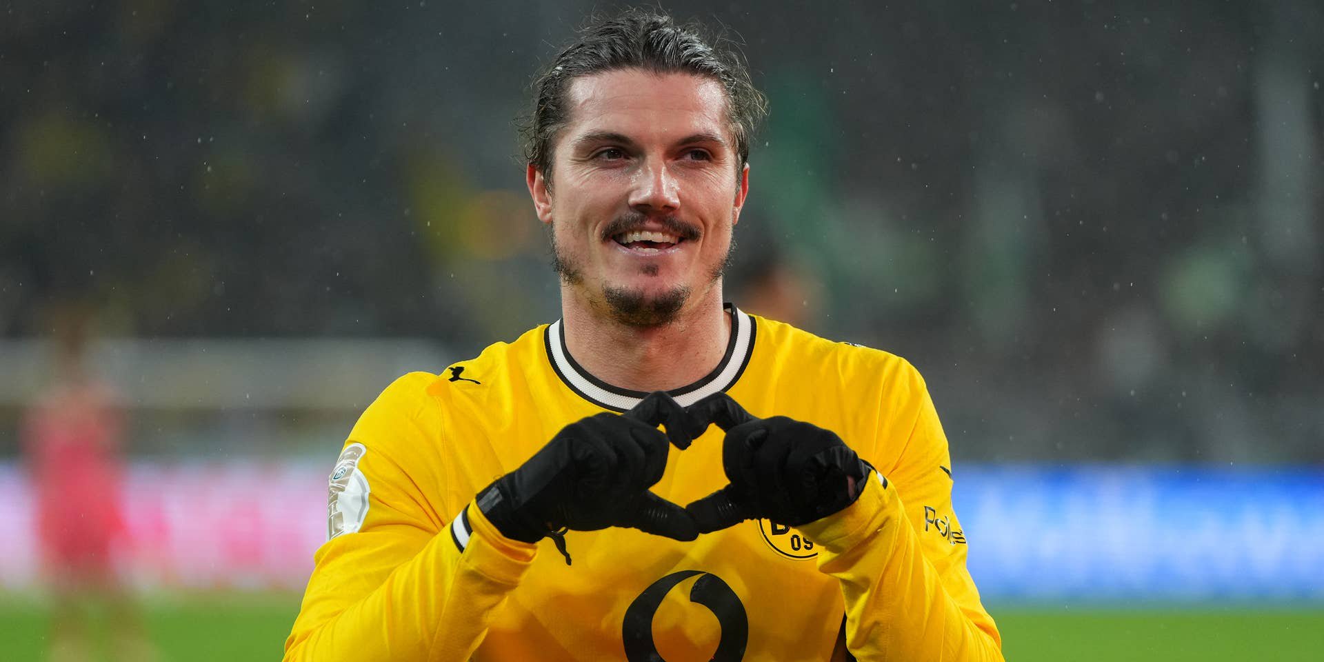 Ein Fußballspieler von Borussia Dortmund jubelt auf dem Spielfeld mit einem Herzzeichen.