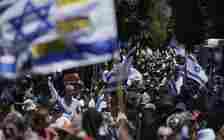 Demonstrators march with Israeli flags during a protest marking nine months since the start of the war and calling for elections and the release of hostages held in the Gaza Strip in Tel Aviv, July 7, 2024. (AP Photo/Leo Correa)