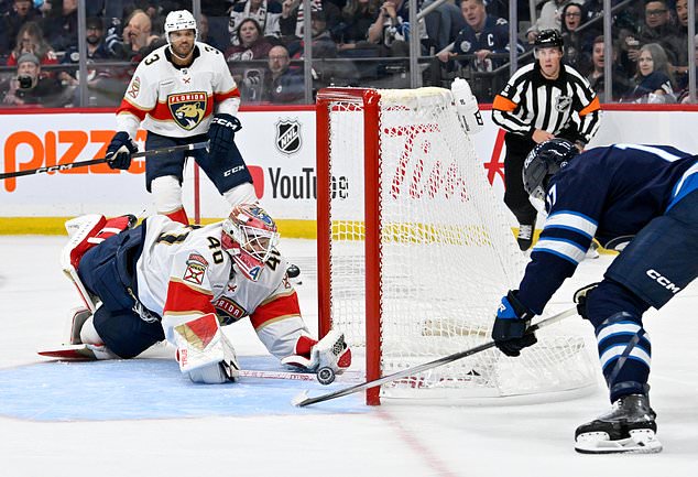 Winnipeg Jets' Adam Lowry (17), right, scores on Florida Panthers' goaltender Akira Schmid (40) during the second period of an NHL hockey game in Winnipeg, Manitoba, Tuesday, Oct. 27, 2026. (Fred Greenslade/The Canadian Press via AP)