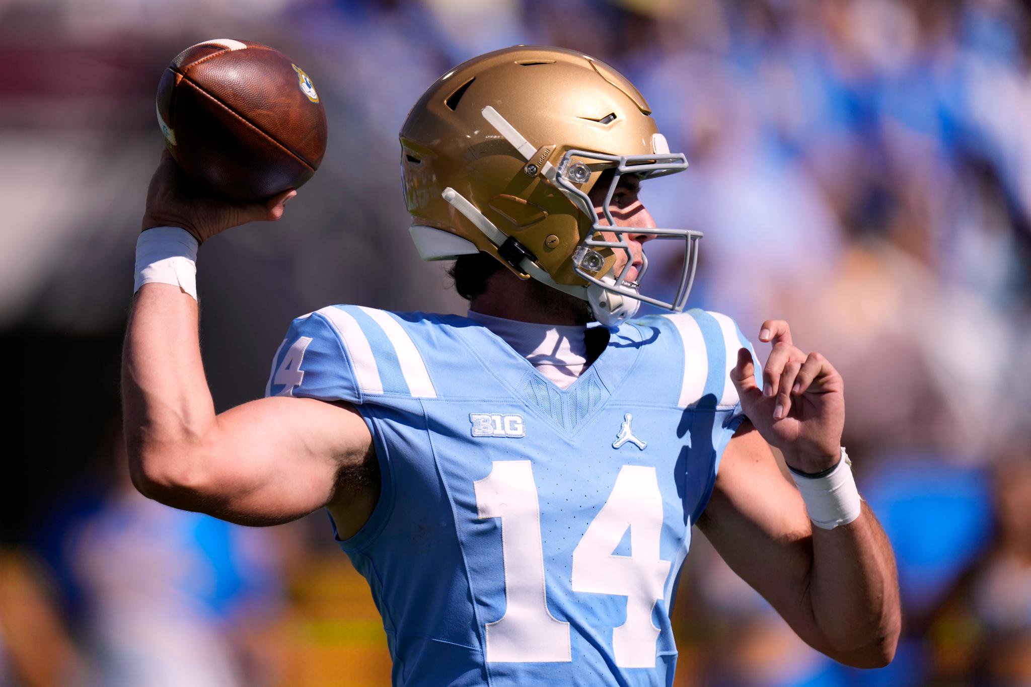 Ty Dieffenbach in a light blue jersey, wearing a gold helmet, prepares to throw a football.