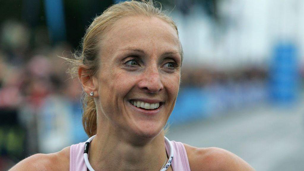 Paula Radcliffe smiles after winning the BUPA Great South Run on October 26, 2008 in Portsmouth, England. Se is smiling with her blonde hair tied back. She has a white necklace and is wearing a pink vest top. 