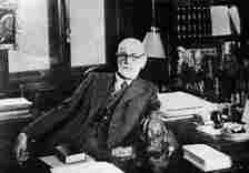 Portrait of Austrian psychologist Sigmund Freud as he sits behind his desk in his study in Vienna, Austria