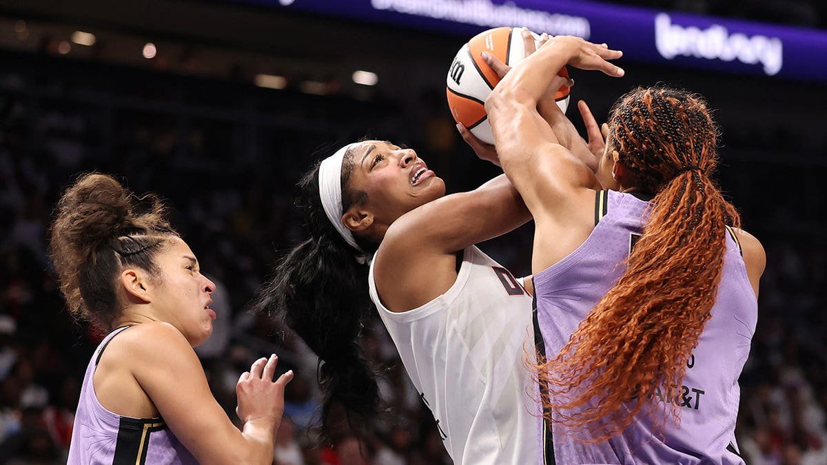 Angel Reese #5 shoots against Kiah Stokes #41 and Veronica Burton #22 during WNBA Finals game.