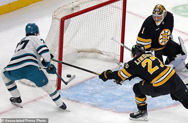 Boston Bruins goalie Jeremy Swayman (1) watches as San Jose Sharks center Michael Misa, left, scores a first-period goal past Bruins defenseman Hampus Lindholm (27) during the first period of an NHL hockey game Saturday, Oct. 24, 2026, in Boston. (AP Photo/Jim Davis)