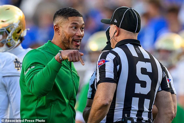 Notre Dame head coach Marcus Freeman, left, has a discussion with sideline judge Chris Junjulas, right, during the first half of an NCAA college football game against BYU, Saturday, Oct. 17, 2026, in Provo, Utah. (AP Photo/Tyler Tate)