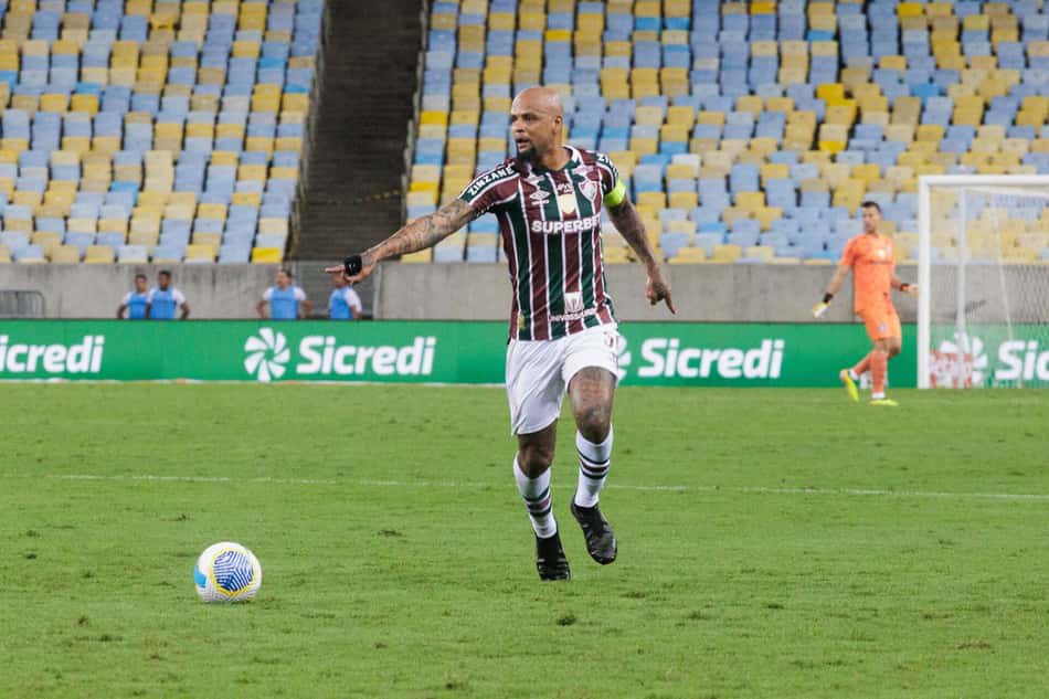 Felipe Melo jogando com a camisa do Fluminense e apoontando 