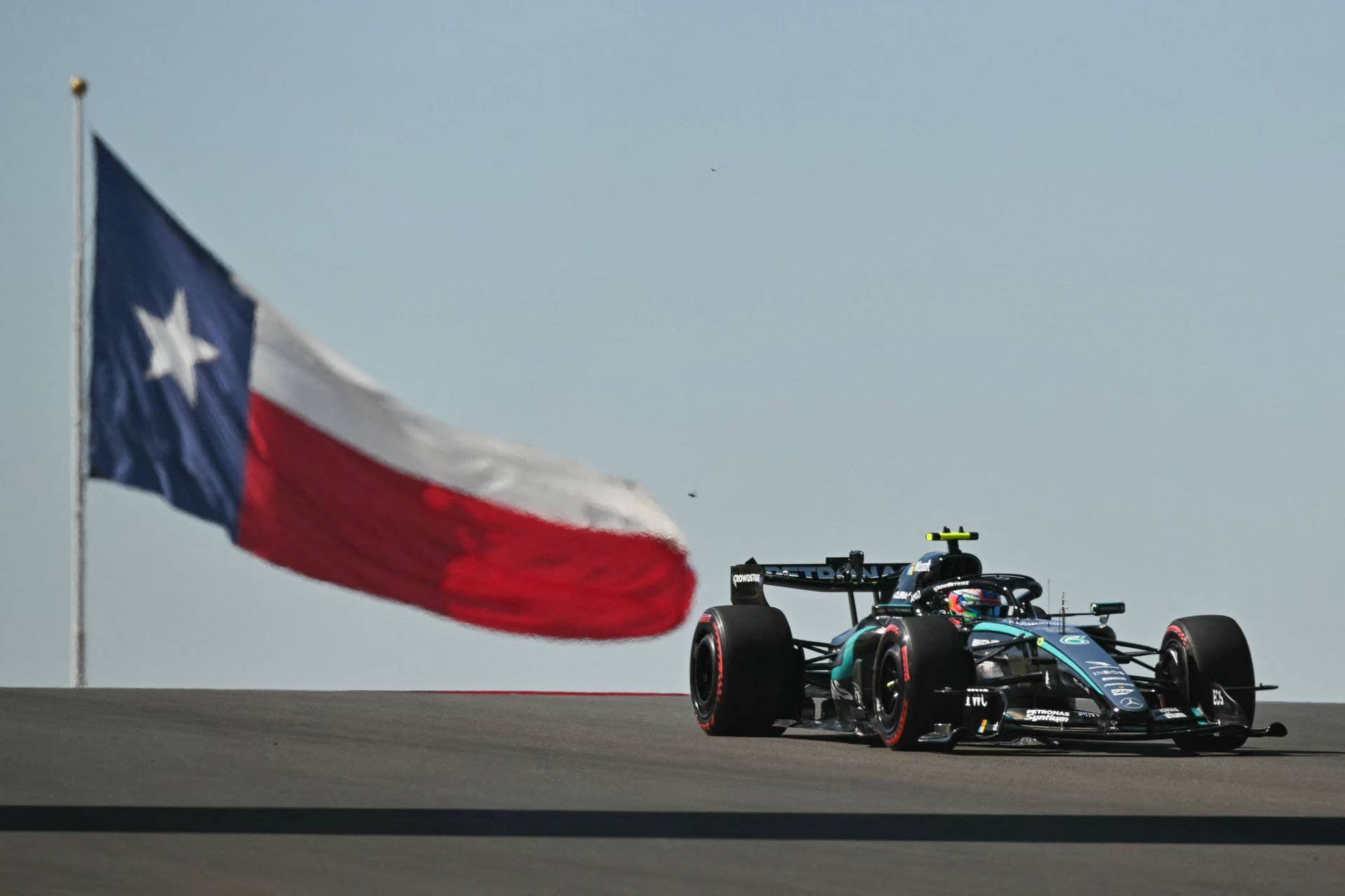 Ein Mercedes-Formel-1-Rennwagen fährt auf dem Circuit of The Americas an einer großen Flagge des US-Bundesstaates Texas vorbei.