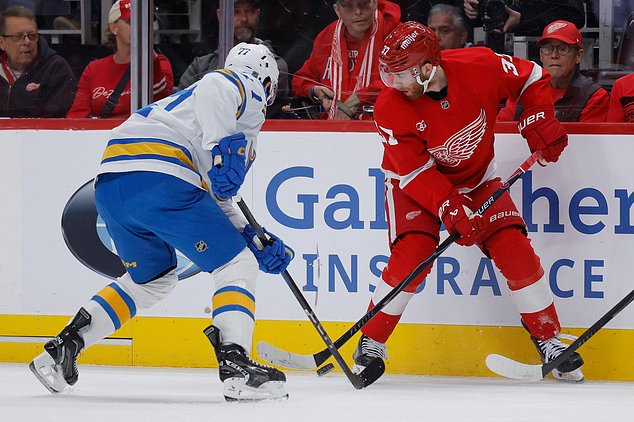 Detroit Red Wings left wing J.T. Compher (37) tries to pass the puck as St. Louis Blues left wing Connor McMichael, left, defends during the first period of an NHL hockey game Saturday, Oct. 31, 2026, in Detroit. (AP Photo/Duane Burleson)