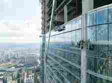 Workers installing glass on tall buildings