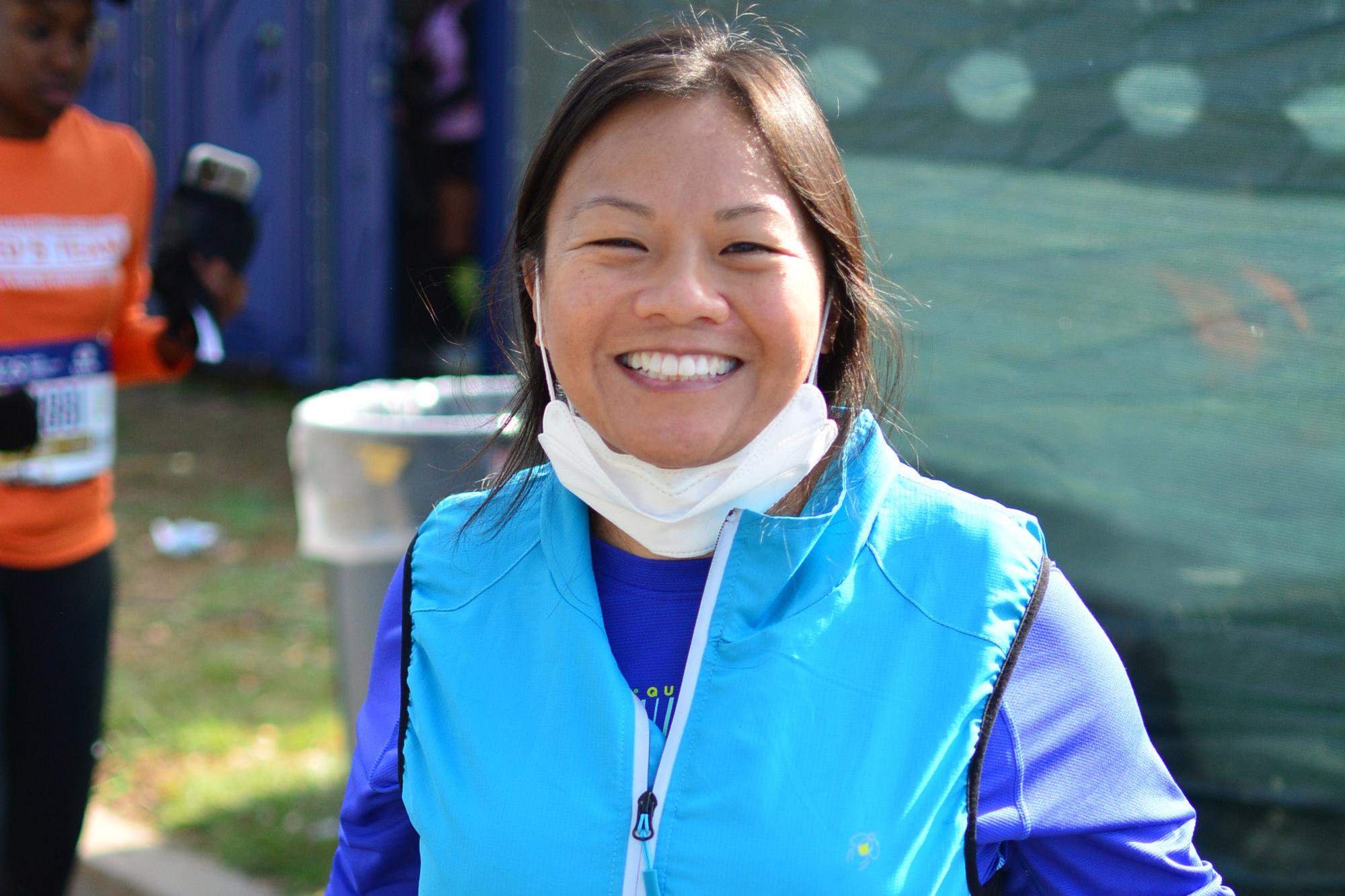 Fredilyn Bangwa smiles during the NYC Marathon with a face mask pulled down under her chin.