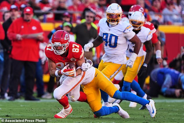 Kansas City Chiefs tight end Travis Kelce (87) catches a pass and is tackled by Los Angeles Chargers linebacker Daiyan Henley, rear, during the first half of an NFL football game in Kansas City, Mo., Sunday, Oct. 18, 2026. (AP Photo/Charlie Riedel)