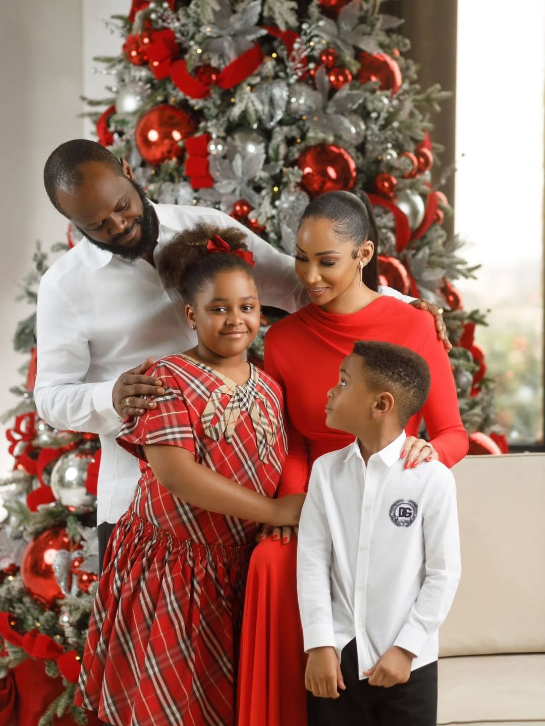 Seyi Tinubu poses with his family in coordinated festive outfits in front of a decorated Christmas tree