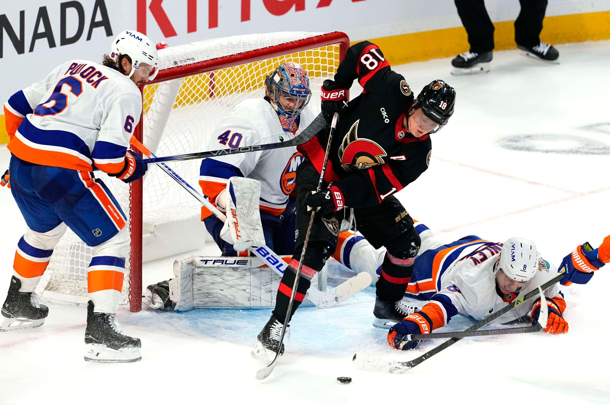 Ottawa Senators' Tim Stutzle (18) tries to the puck as New York Islanders' Logan Stanley (8) and Ryan Pulock (6) defend in front of Islanders goaltender Semyon Varlamov (40) during overtime NHL hockey game action in Ottawa, Ontario, Thursday, Oct. 15, 2026.