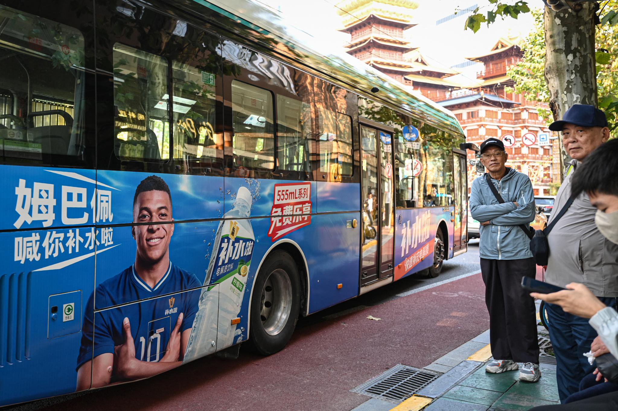 A bus featuring an advertisement of French football star Kylian Mbappe for Dongpeng Beverage Group's "Bushuila" electrolyte drink on a street in Shanghai.