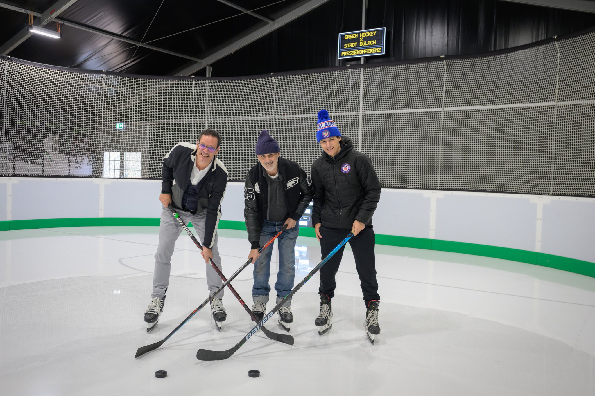 Daniel Ammann, Riccardo Signorell und Demian Gramegna posieren mit Hockeyschlägern auf dem provisorischen Kunsteisfeld der Oceanice Pop-up-Arena in Bülach.