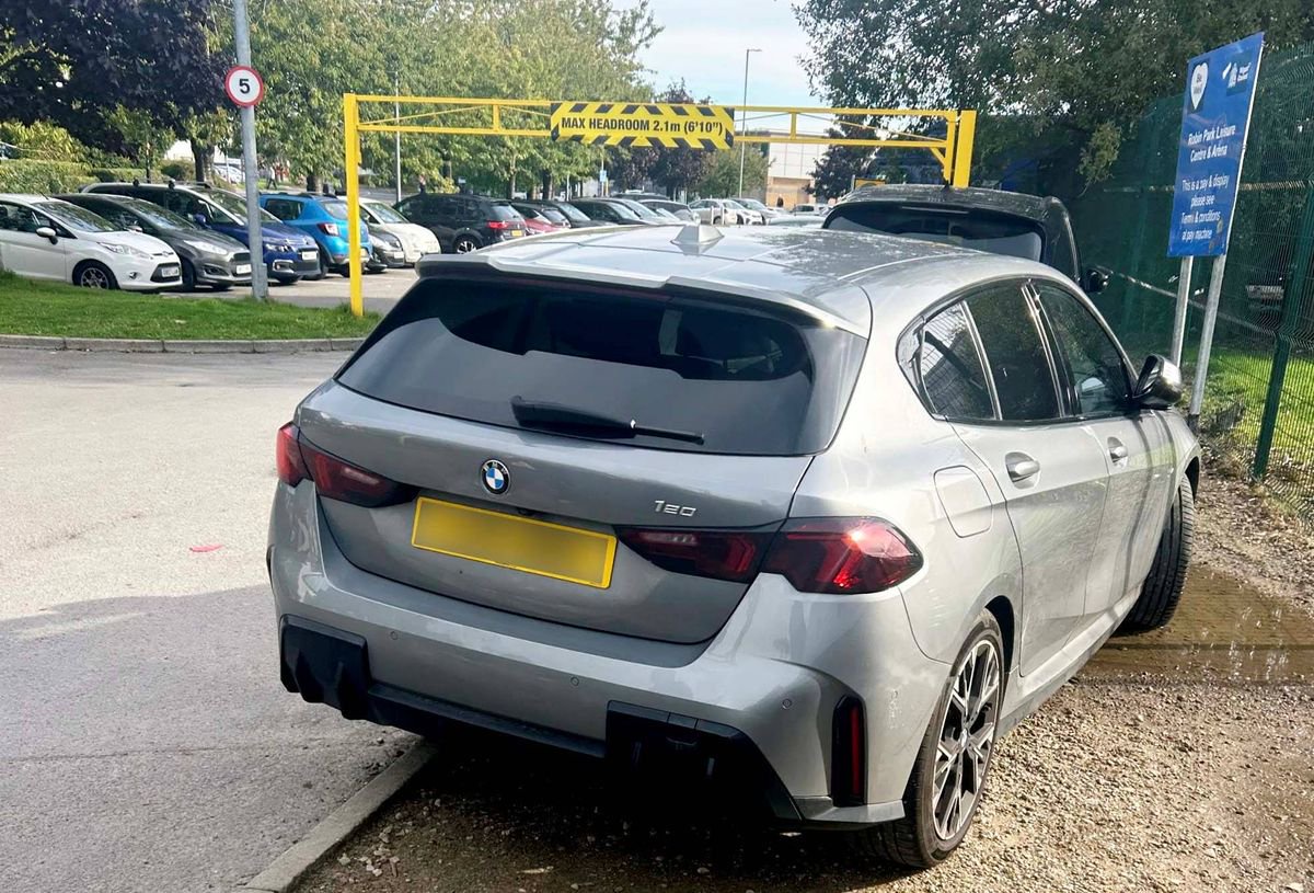 Luke Littler's BMW pictured from behind parked at an angle facing rightwards outside the entrance to a car park