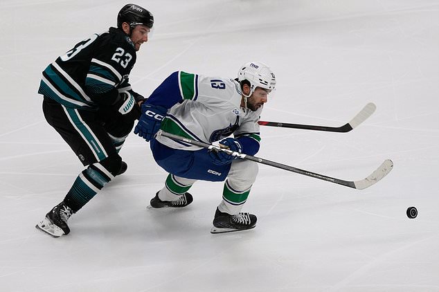 Vancouver Canucks left wing Arshdeep Bains, right, skates toward the puck against San Jose Sharks center Barclay Goodrow (23) during the third period of an NHL hockey game, Thursday, Oct. 29, 2026, in San Jose, Calif. (AP Photo/Jeff Chiu)