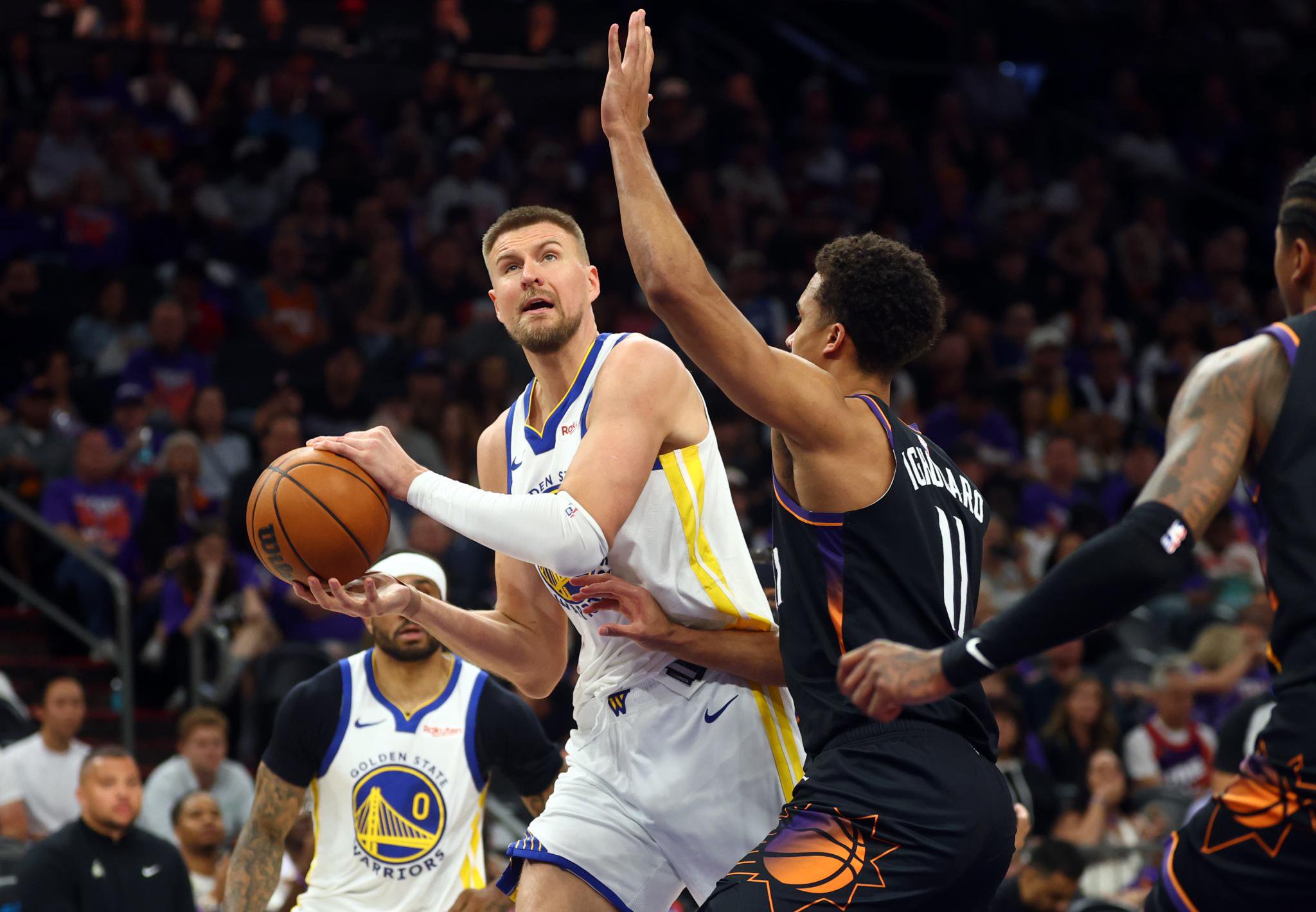 Golden State Warriors Kristaps Porzingis driving to the basket against Phoenix Suns Oso Ighodaro.