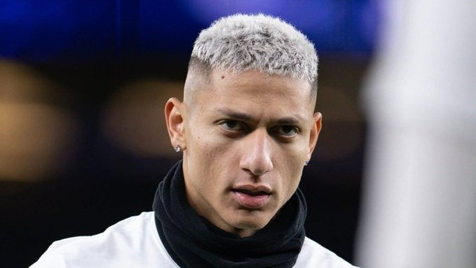 Rosto do jogador Richarlison, cabelo platinado, usando brincos e gola preta