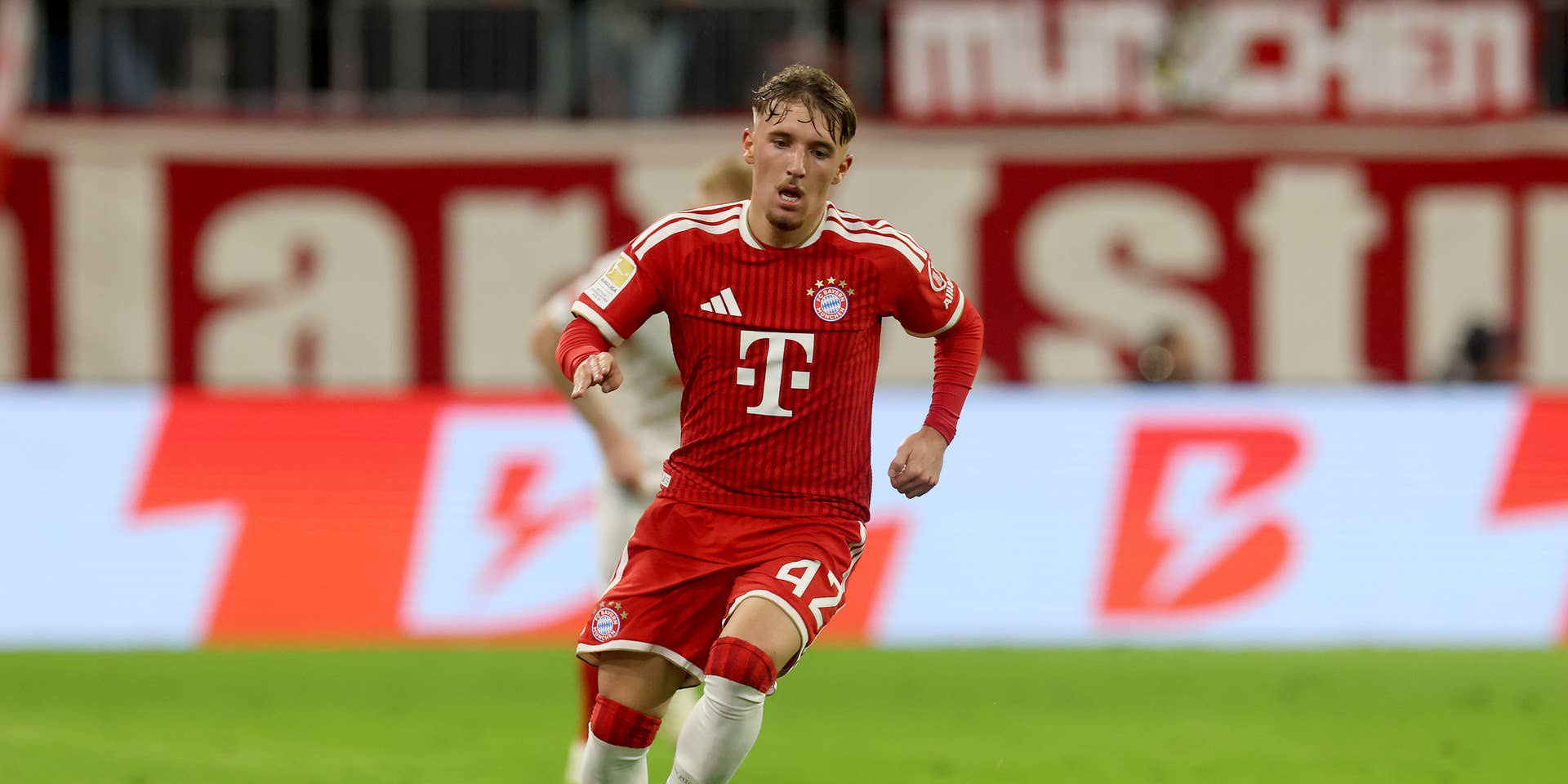 Ein FC Bayern-Spieler im roten Trikot läuft mit dem Ball über das Spielfeld in der Allianz Arena.