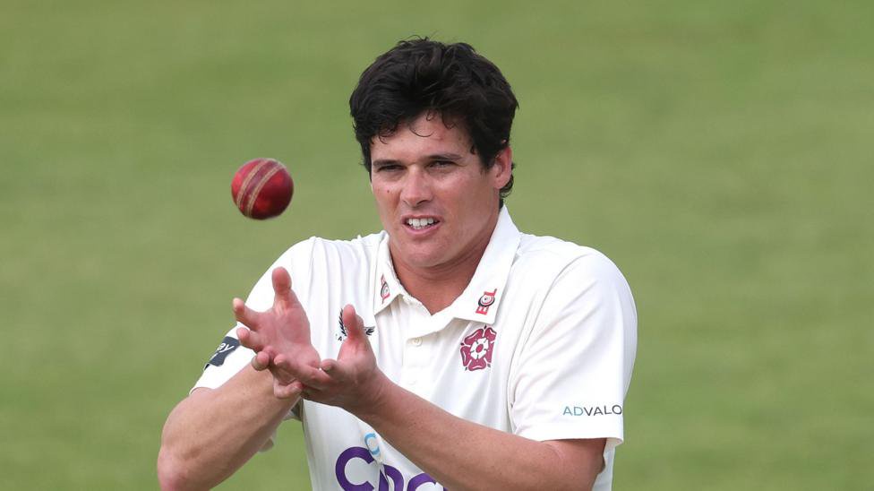 Liam Guthrie catching a red cricket ball during a County Championship match.