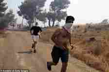 KERATEA -- People cover their faces as they run from a wildfire