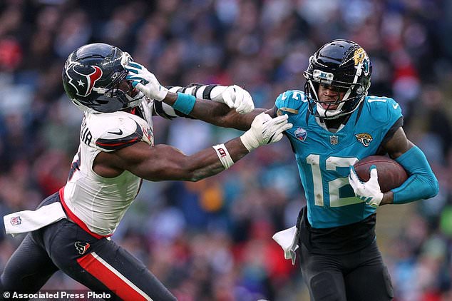 Jacksonville Jaguars wide receiver Travis Hunter (12) holds off Houston Texans linebacker Azeez al-Shaair (0) during an NFL football game in London, Sunday, Oct. 18, 2026. (AP Photo/Ian Walton)