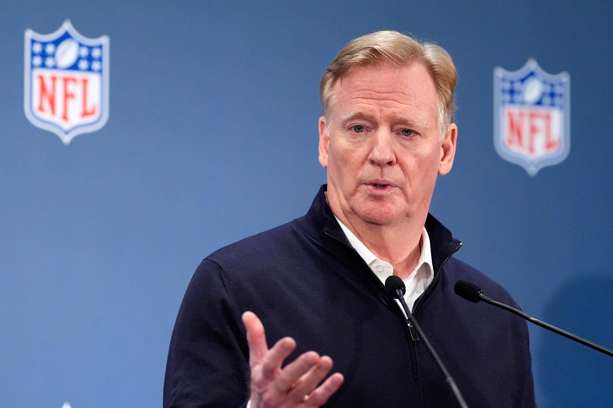 NFL commissioner Roger Goodell speaks at a news conference in front of a blue backdrop featuring NFL logos.
