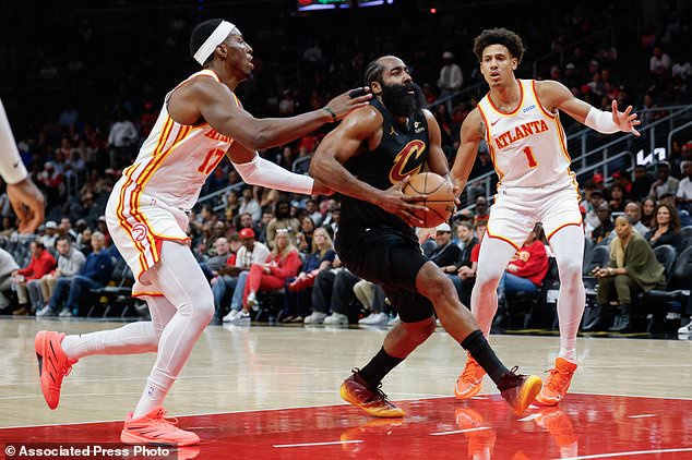Cleveland Cavaliers guard James Harden, center, drives against Atlanta Hawks forwards Onyeka Okongwu (17) and Jalen Johnson (1) during the first half of an NBA basketball game, Thursday, Oct. 29, 2026, in Atlanta. (AP Photo/Erik S. Lesser)