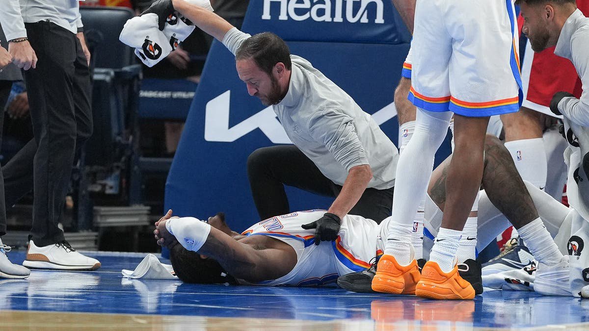 Jalen Williams is attended to by medical staff during an NBA basketball game.