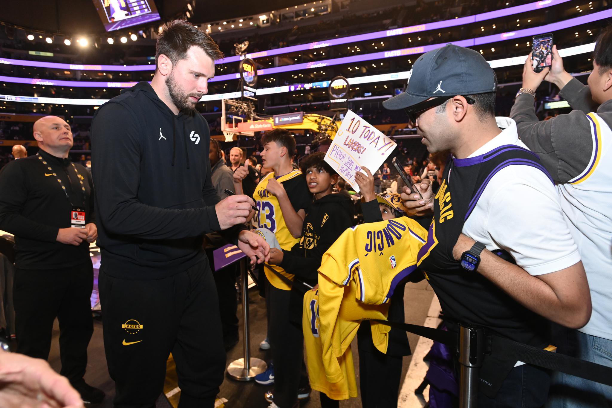 Luka Doncic signs autographs for fans in the stands before a game against the Los Angeles Lakers.