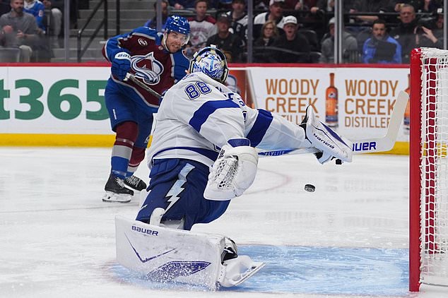 Colorado Avalanche defenseman Devon Toews, back, shoots the puck past Tampa Bay Lightning goaltender Andrei Vasilevskiy (88) for a goal in the first period of an NHL hockey game Friday, Oct. 23, 2026, in Denver. (AP Photo/David Zalubowski)