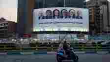 Vehicles move past a billboard displaying the faces of the six candidates running in the upcoming Iranian presidential election in Valiasr Square in central Tehran on 15 June 2024 (