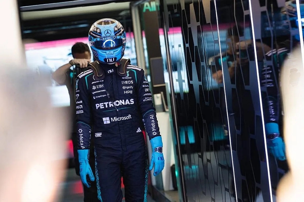 Driver in navy Petronas Mercedes F1 suit and blue helmet walking in the pit garage, Formula 1