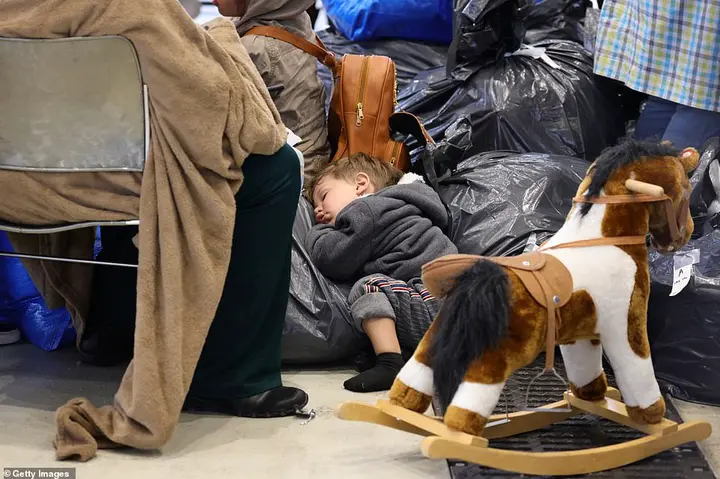 A toddler sleeps on trash bags next to a rocking horse at Ramstein Air Base in Germany after being flown out of Kabul