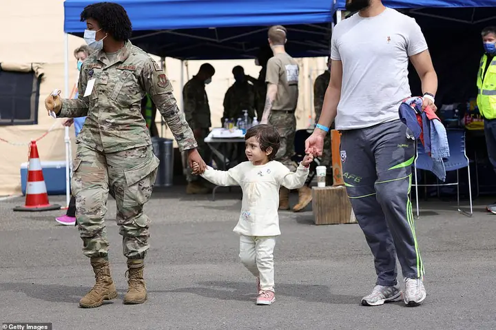 A father and child from Afghanistan walk together with a medical officer after their arrival to Ramstein Air Base on August 26