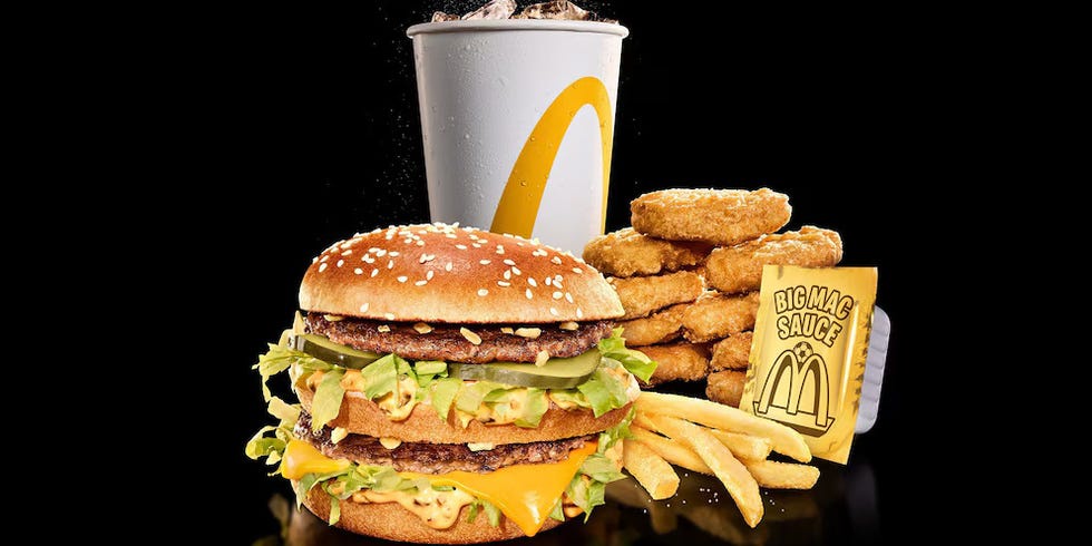 Big Mac meal with burger, fries, nuggets, sauce, and drink on black background.
