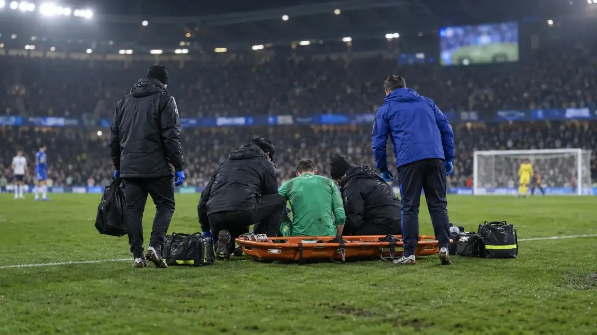 Medical staff attend an injured goalkeeper on a football pitch beside a stretcher