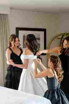 Bride in Wedding Dress Getting Ready With Bridesmaids in Black Dresses 