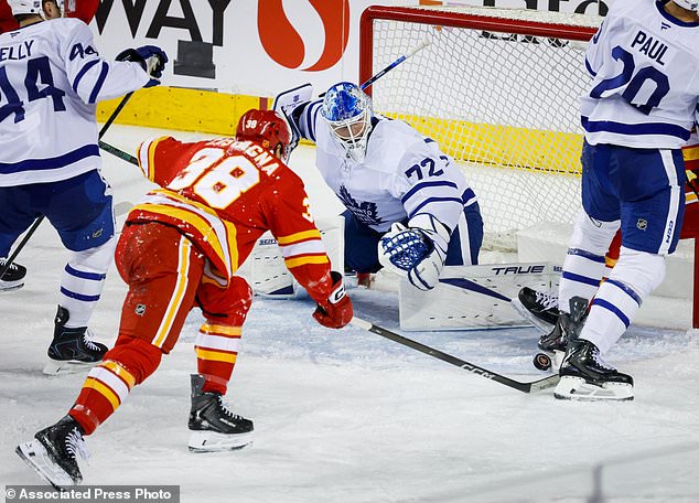 Toronto Maple Leafs goalie Sergei Bobrovsky, center, scrambles for a lose puck as Calgary Flames' Jonathan Castagna, left, reaches for it during the second period of an NHL hockey game in Calgary, Alberta, Monday, Oct. 26, 2026. (Jeff McIntosh/The Canadian Press via AP)
