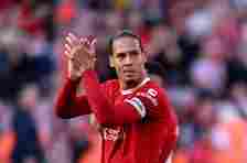 Virgil van Dijk clapping the Liverpool fans while wearing the all red 2023/24 home kit. He is also wearing the captain's armband.