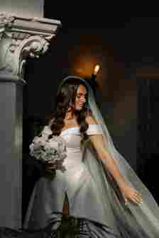 Bride in Wedding Dress With Long Veil Holding White Bouquet 