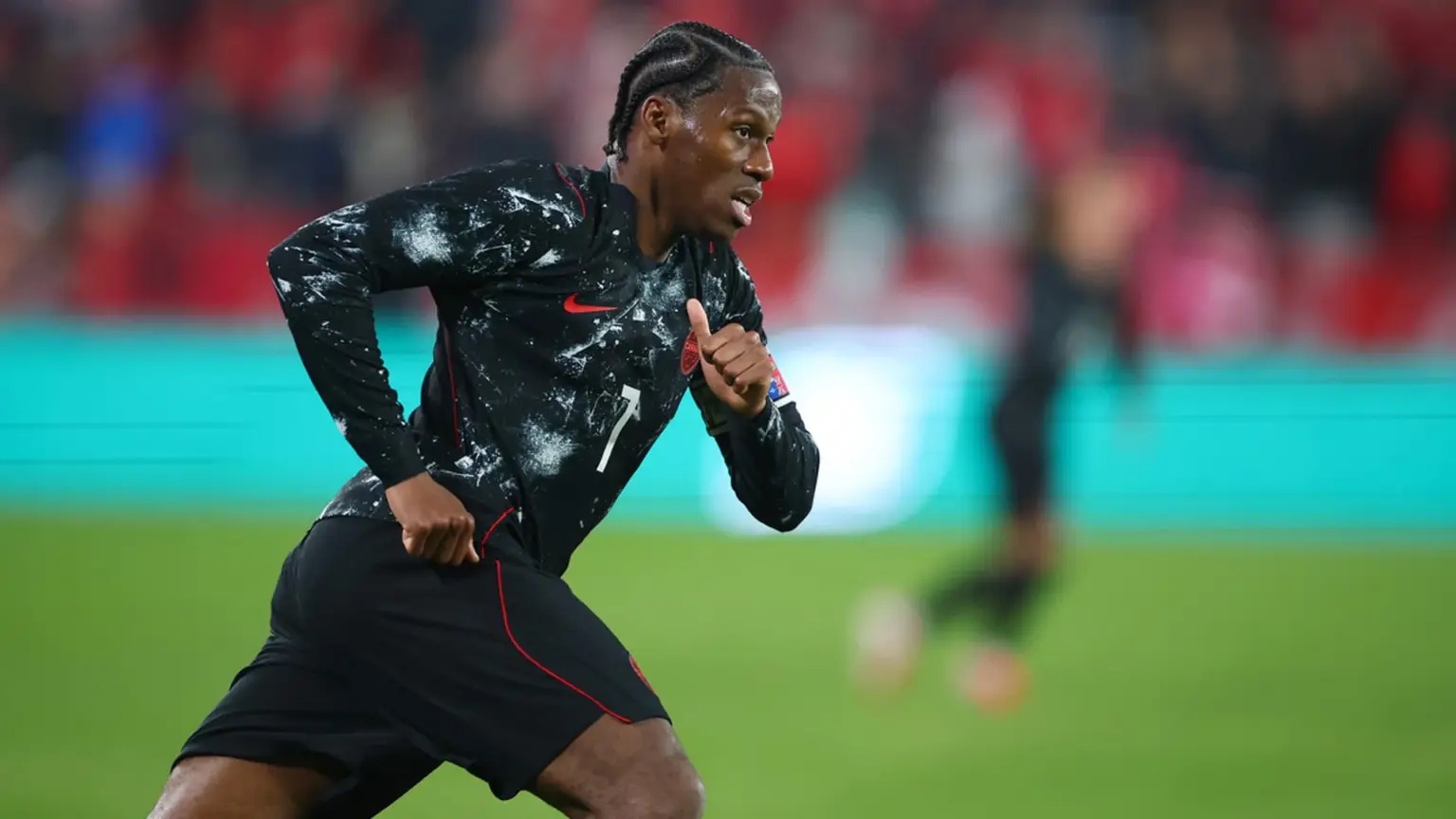 Jonathan David in a black Canada national team kit running during a match