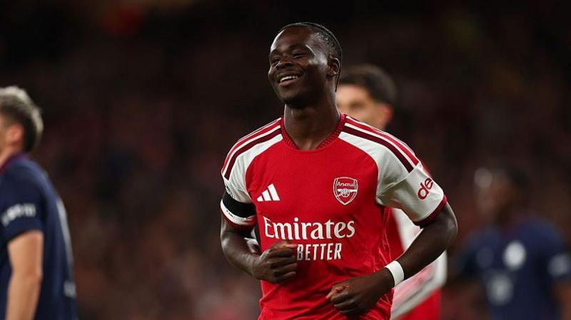 A smiling Bukayo Saka in Arsenal's red and white kit