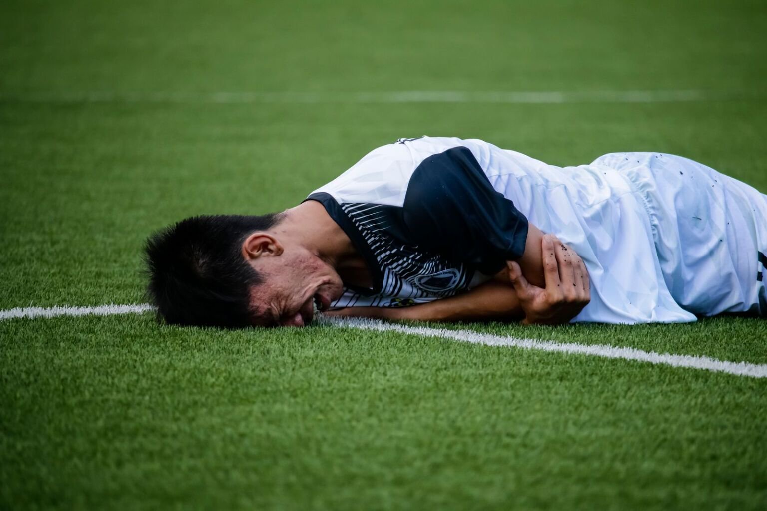 Footballer in a white and dark kit lying injured on the pitch, illustrating the Juventus injury news