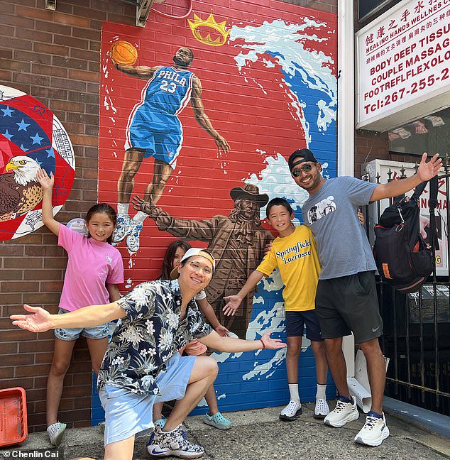 Chenlin Chai (kneeling) poses with others in front of his popular mural in Philly's Chinatown