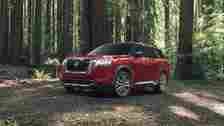 Red 2023 Nissan Pathfinder front 3/4 exterior shot parked in a forest