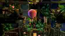 Luigi with his vacuum attached to a floating pink balloon Luigi's Mansion 2 HD.