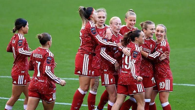 Liverpool players, wearing red, celebrate their goal